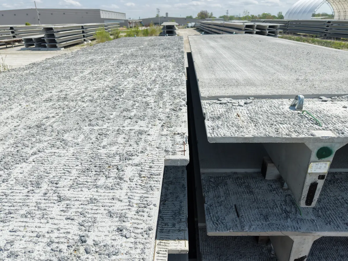 Rows of prestressed concrete bridge girders stored in a precast plant yard.
